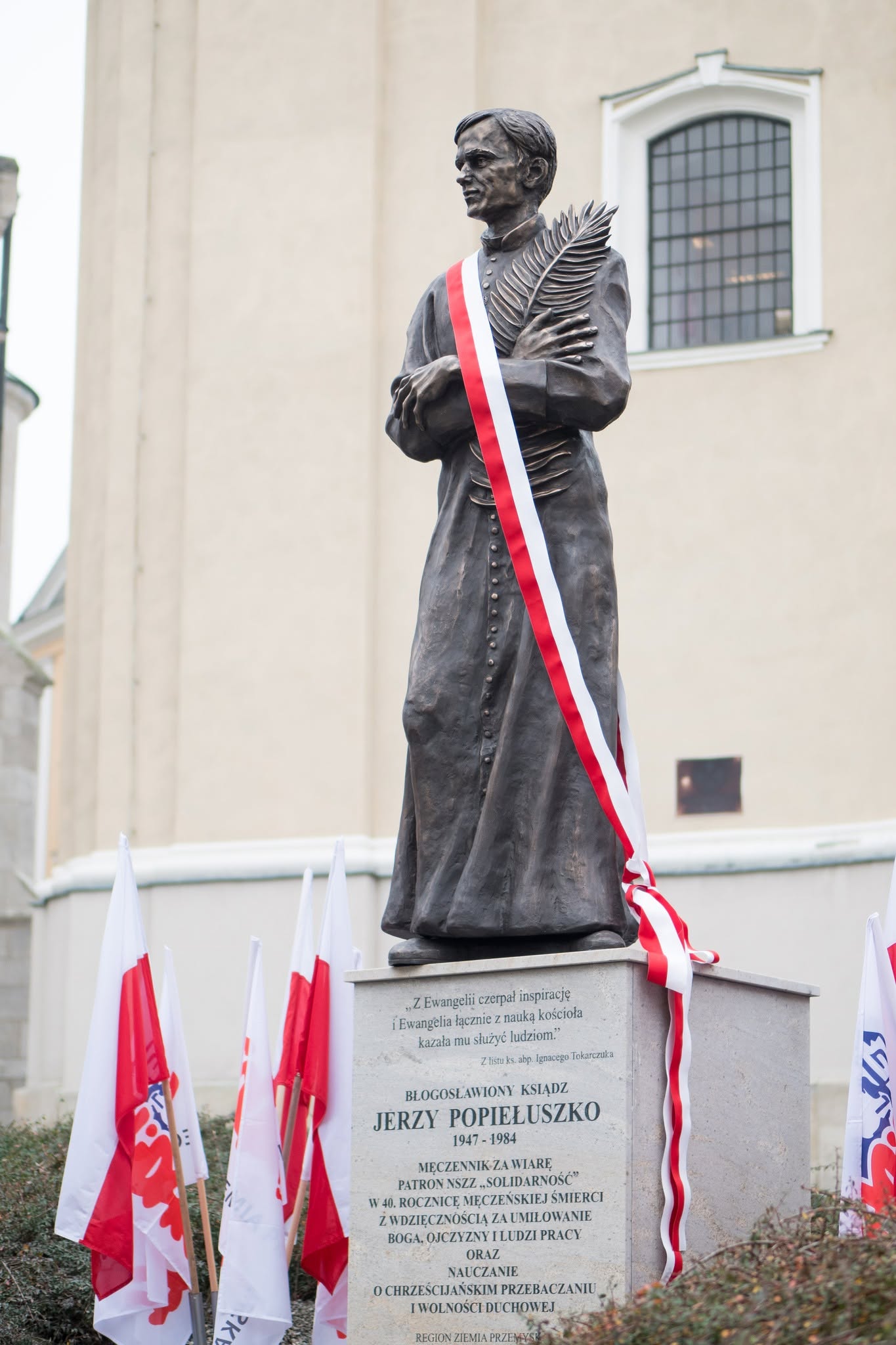 Pomnik ks. Jerzego Popiełuszki podczas uroczystości odsłonięcia, z biało-czerwoną wstęgą.